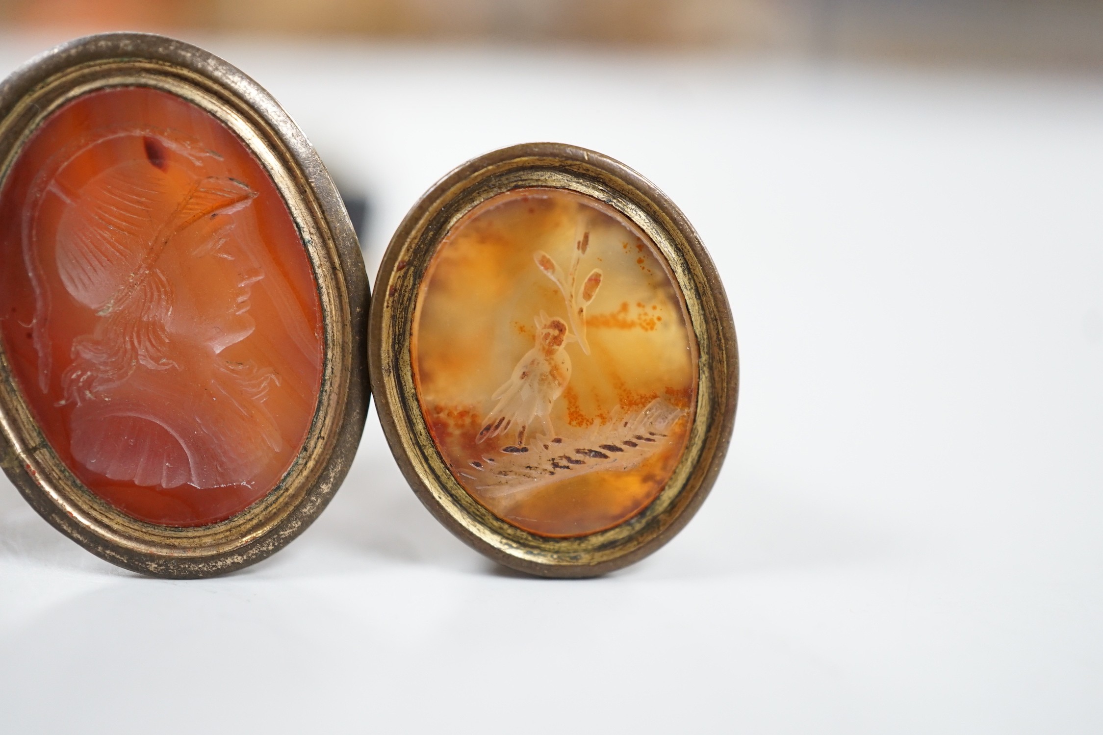 Four assorted 19th century gold plated and agate or hardstone set oval fob seals, largest 37mm, two matrices carved with busts and two with animals.